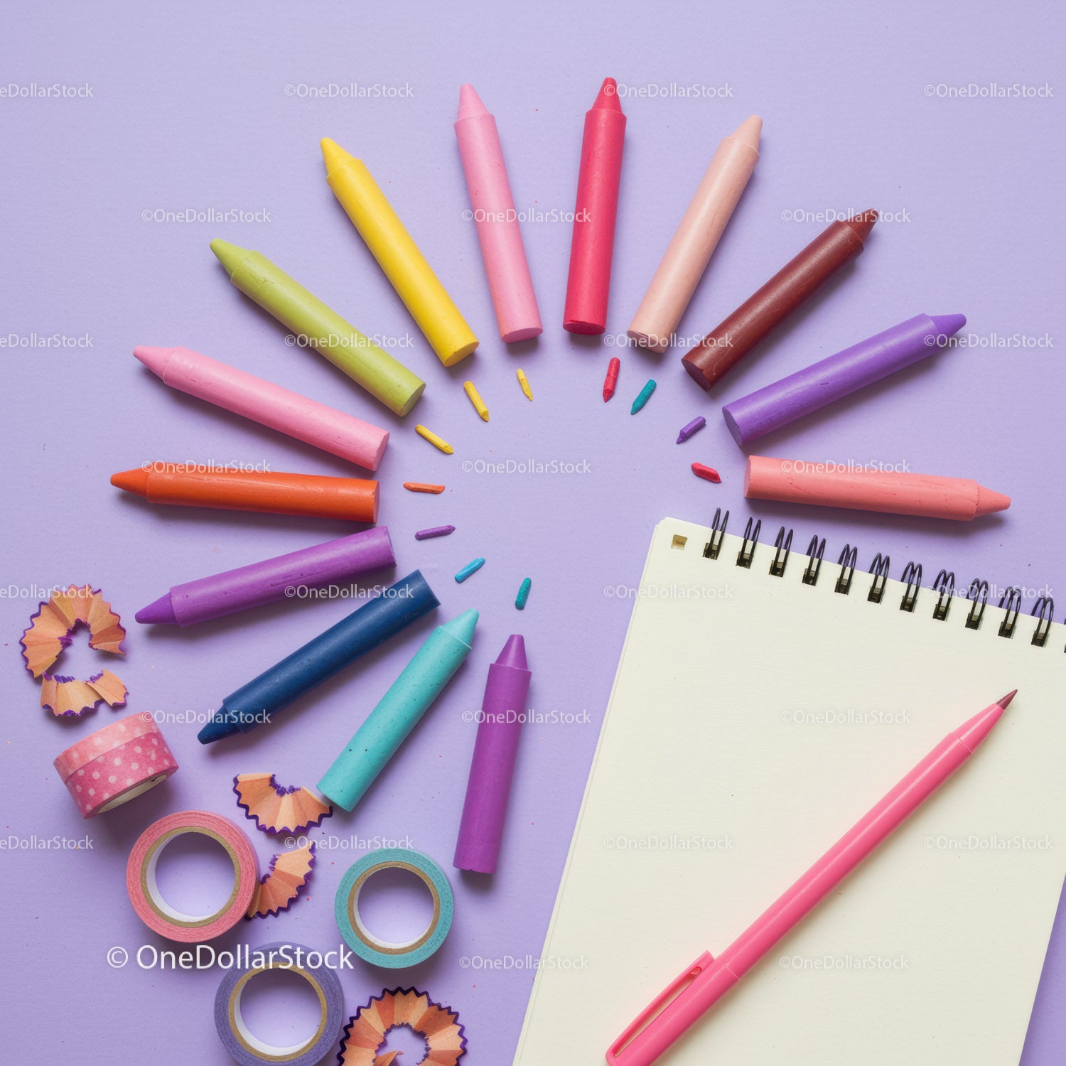 Colorful crayons and notebook on pastel background