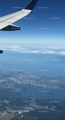 Aerial View of Landscape from Airplane Wing with Blue Sky and Clouds
