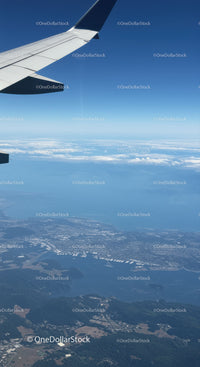 Aerial View of Landscape from Airplane Wing with Blue Sky and Clouds