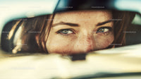 Close-up of a Woman's Eyes Reflected in a Car's Rearview Mirror