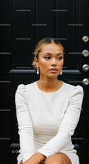 Elegant woman in white dress sitting against black door