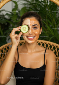 Young Woman with Facial Mask and Cucumber in Natural Green Setting