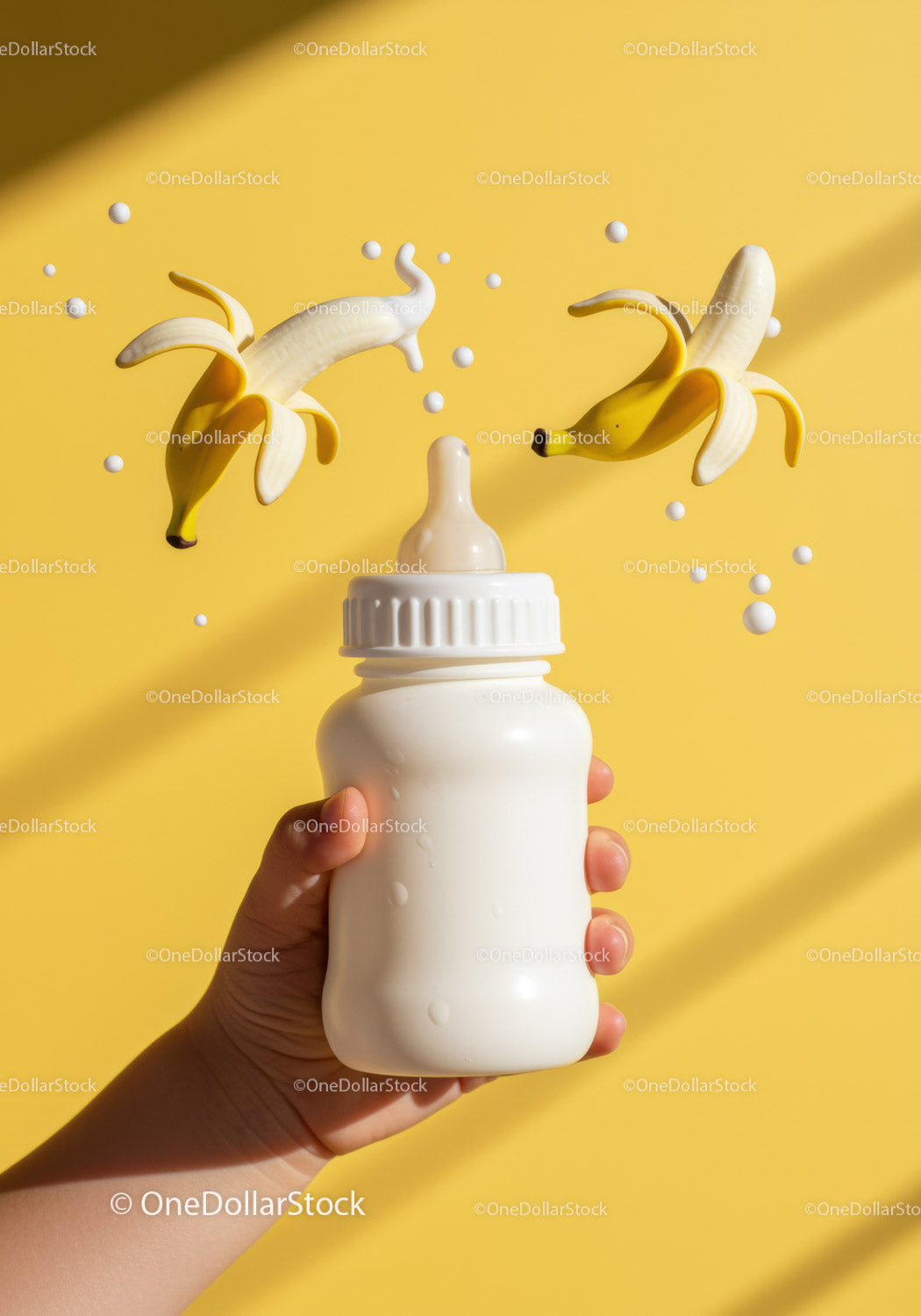 Dłoń trzymająca butelkę dla dziecka z unoszącymi się bananami i mlekiem