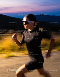 Woman Running Fast Along Mountain Road at Sunset