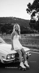 Young woman in white dress roller skating on car hood