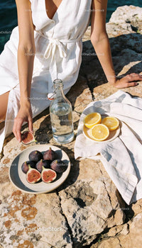 Woman enjoying fresh figs and lemon slices outdoors