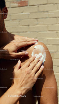 Man applying sunscreen to shoulder on sunny day