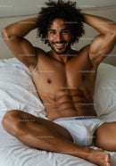 Smiling man relaxing on bed in white underwear