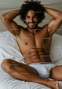 Smiling man relaxing on bed in white underwear