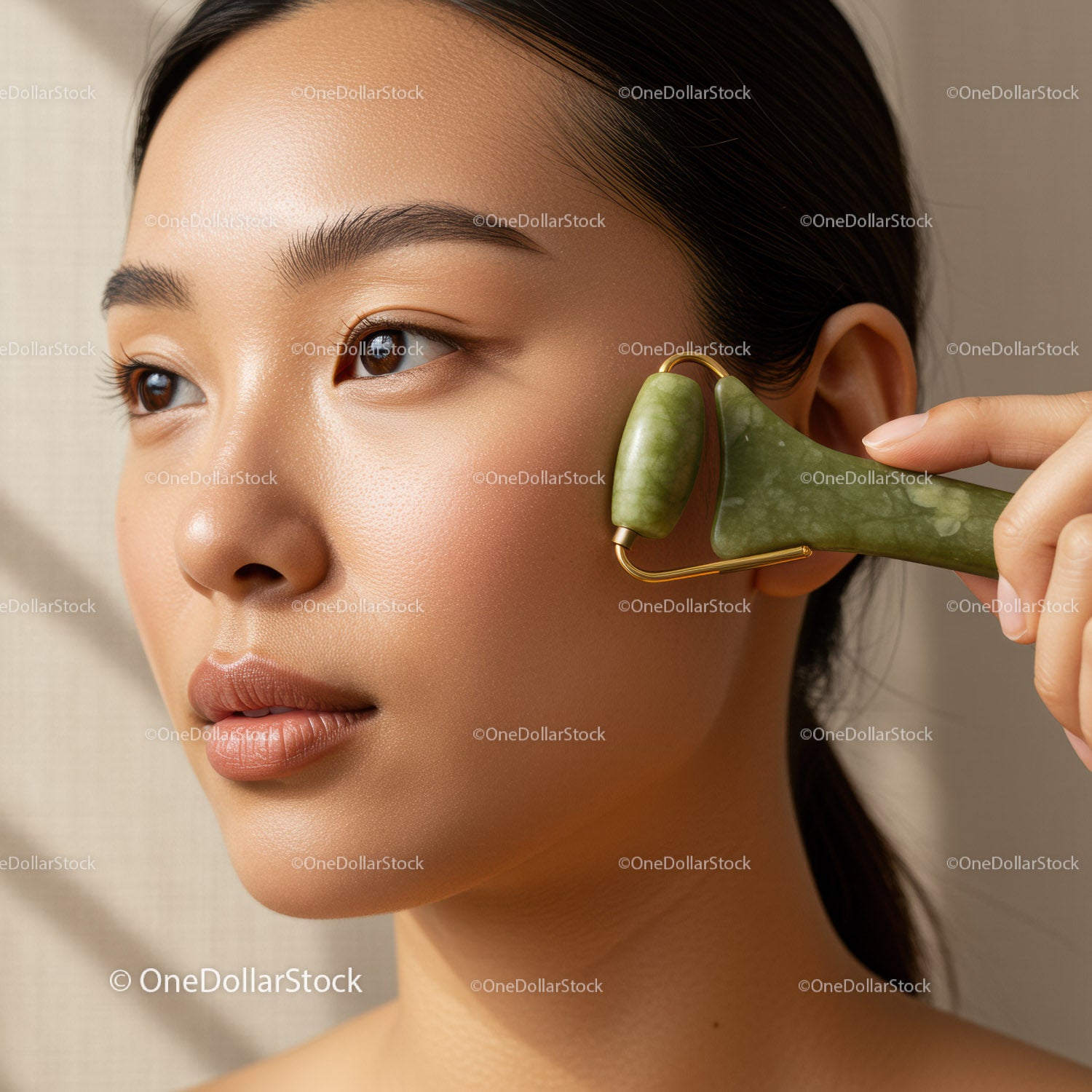 Close-up of Asian woman using jade roller on face for skincare rejuvenation