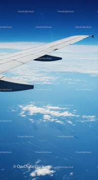 Aerial View of Airplane Wing Over Cloudscape and Blue Sky