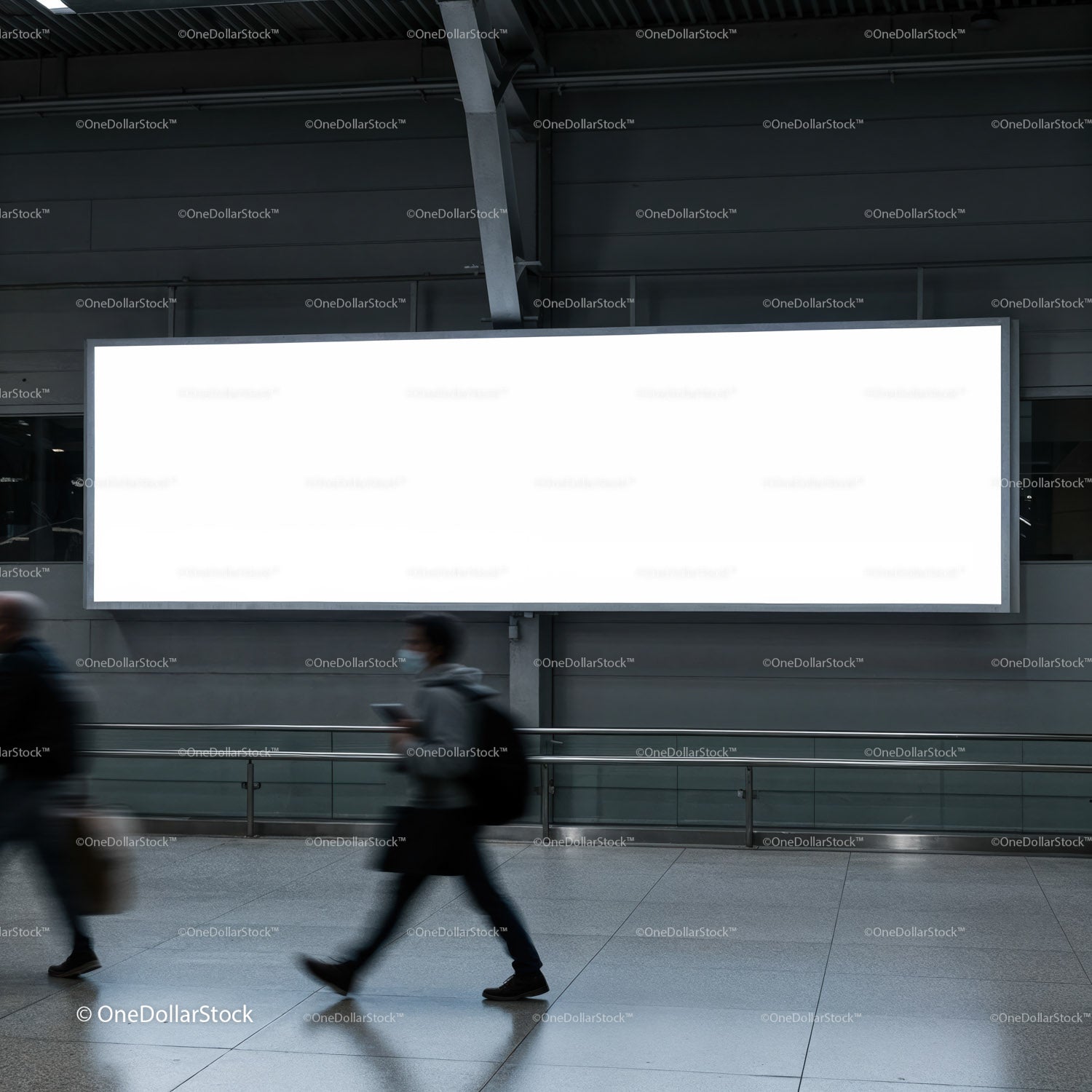 Commuters walking past large blank billboard indoors