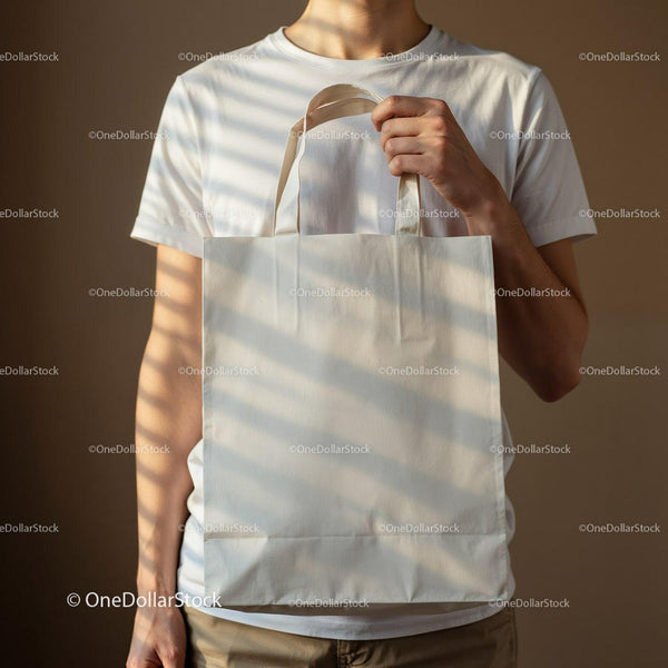 Man Holding Blank Canvas Tote Bag with Sunlight Shadows JPG Mockup Image