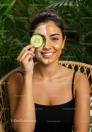 Smiling Woman with Facial Mask and Cucumber Slice in Lush Green Environment