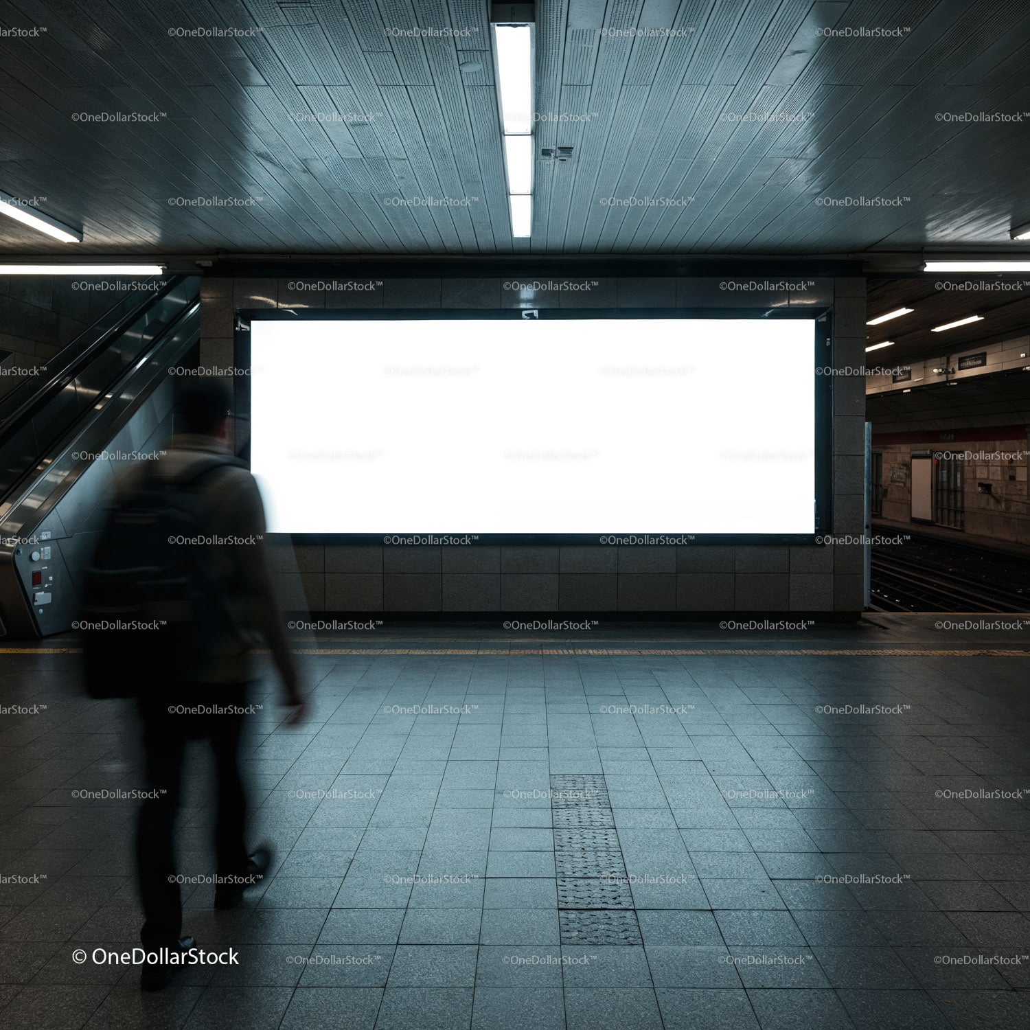 Pasażer przechodzi obok pustego, oświetlonego billboardu w metrze