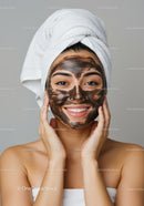 Young Woman with Black Facial Mask Applying Skincare Routine
