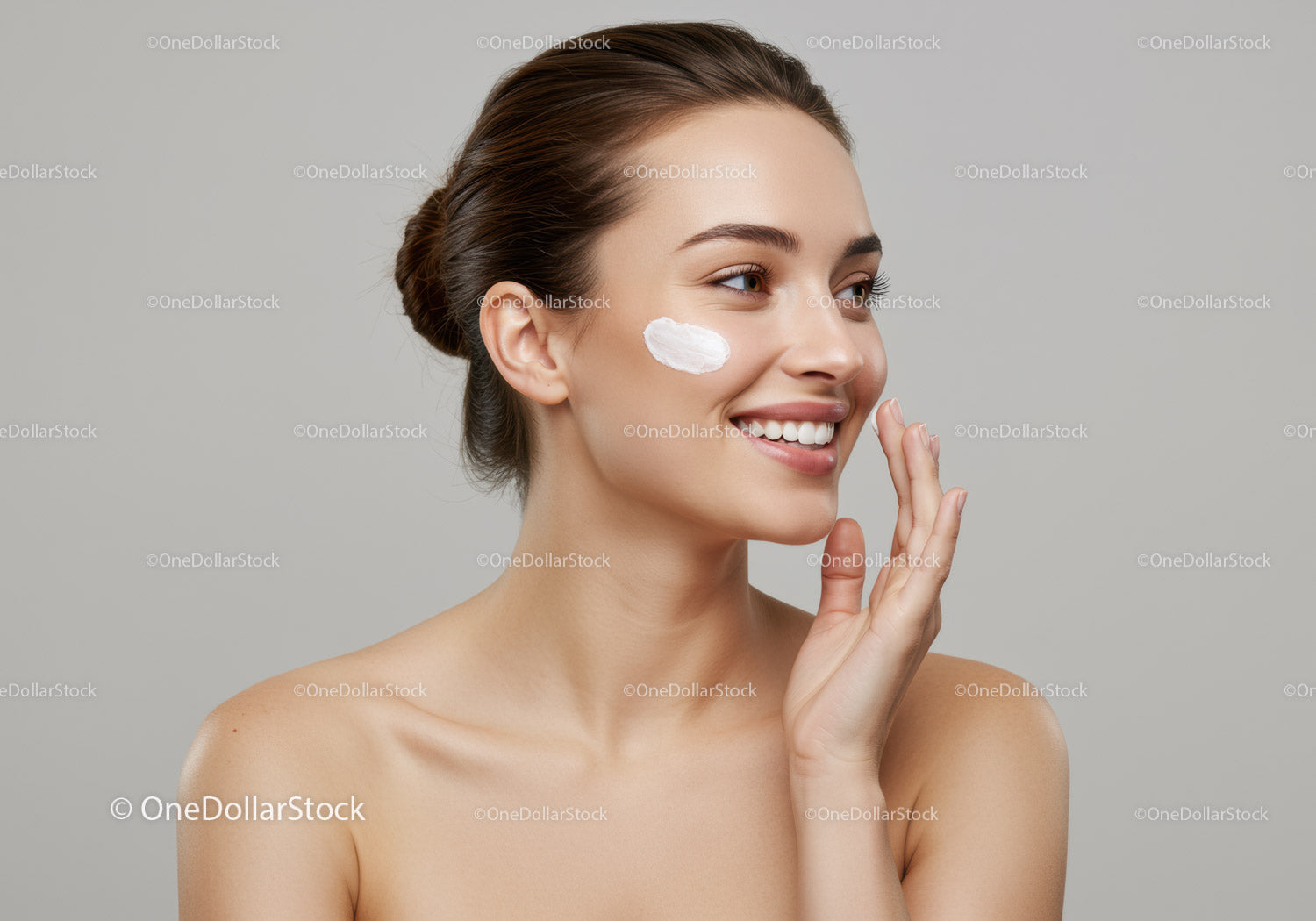 Young Woman with Perfect Skin Applying Moisturizer on Cheek