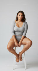 Portrait of a Confident Woman Sitting on a Stool in Gray Outfit