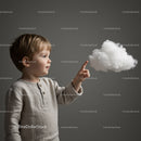 Young boy touching a floating cotton cloud indoors