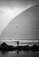 Solitary figure observing ocean waves at rocky shore