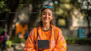 Young Woman in Bright Orange Jacket Using Tablet Outdoors