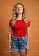 Young woman with curly hair wearing red shirt and denim shorts