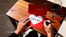 Man writing love message in red card with wine glass