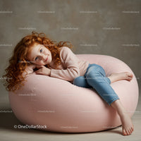 Relaxed red-haired girl lounging on soft pink chair
