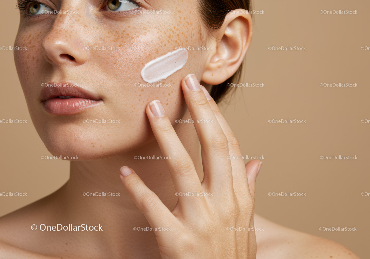 Close-up of a woman applying skincare cream on her face with freckles natural makeup