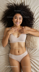 Smiling woman relaxing on bed with natural curly hair