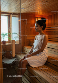 Young Woman Relaxing in Wooden Sauna with Warm Ambient Lighting