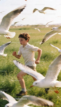 Young boy running joyfully through seagulls in green field