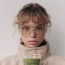 Young Girl with Curly Hair Wearing Sunglasses and Drinking Green Smoothie