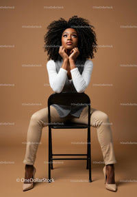 Stylish Black Woman Sitting Confidently on Chair in Fashionable Outfit