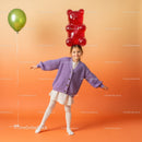 Little girl balancing giant gummy bear on head