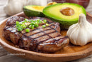 Grilled Steak with Avocado and Garlic on Wooden Plate