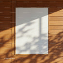 Blank white poster frame on wooden wall with shadows