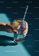 Hand Holding Glass of Sparkling Water with Edible Flowers