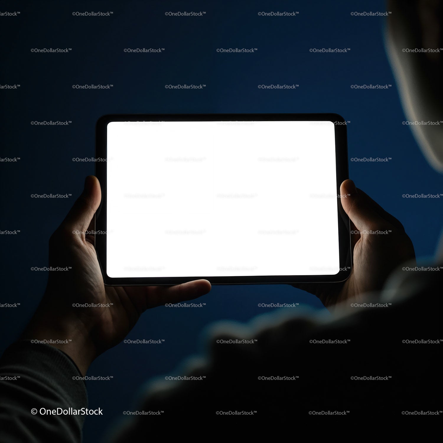 Person holding illuminated digital tablet in dark room