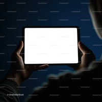 Person holding illuminated digital tablet in dark room