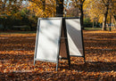 Blank sandwich board signs in autumn park setting
