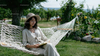 Woman Relaxing in Hammock Reading a Book in Bright Garden