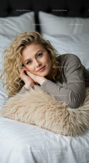 Relaxed young woman lying on bed with cozy pillow