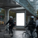 Urban cyclists passing by blank advertising board