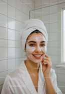 Smiling woman with face mask and eye patches in bathroom
