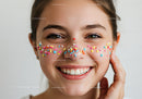 Joyful Girl with Colorful Sprinkles Face Decorations in Bright Studio