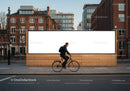 Cyclist riding past large blank urban billboard