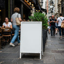 Blank sidewalk sign in bustling city street cafe scene