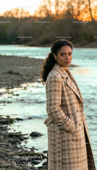 Woman in Cozy Patterned Coat by a Serene Riverbank