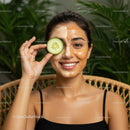 Smiling Woman with Facial Mask Holding Cucumber Slice in Spa Setting